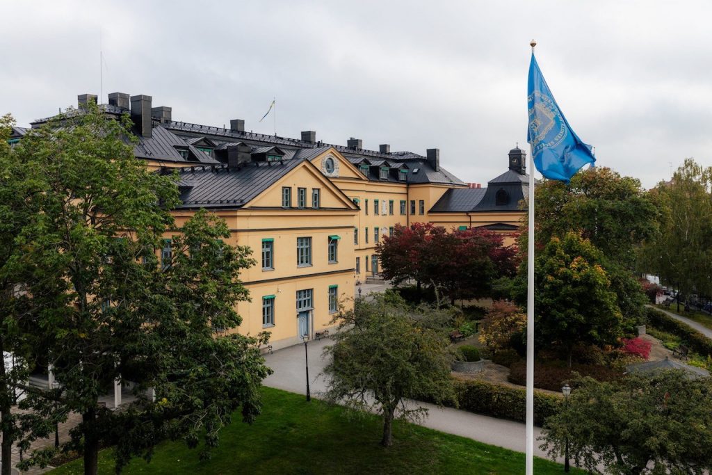 Borgarhemmet på Högalid, omgivet av lummig grönska och en vajande flagga i förgrunden.